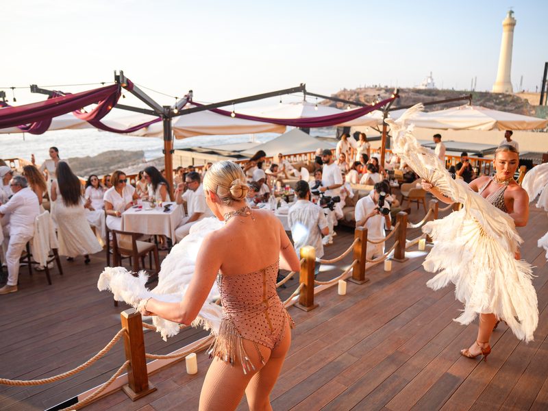 Soirée événementielle en bord de mer : invités en blanc et danseuses à plumes — photographe à Casablanca