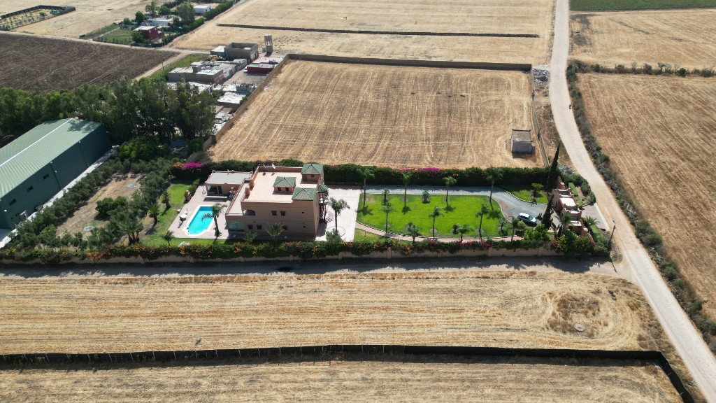Vue aérienne d’une villa de luxe avec piscine, pelouse et bougainvilliers — drone Marrakech