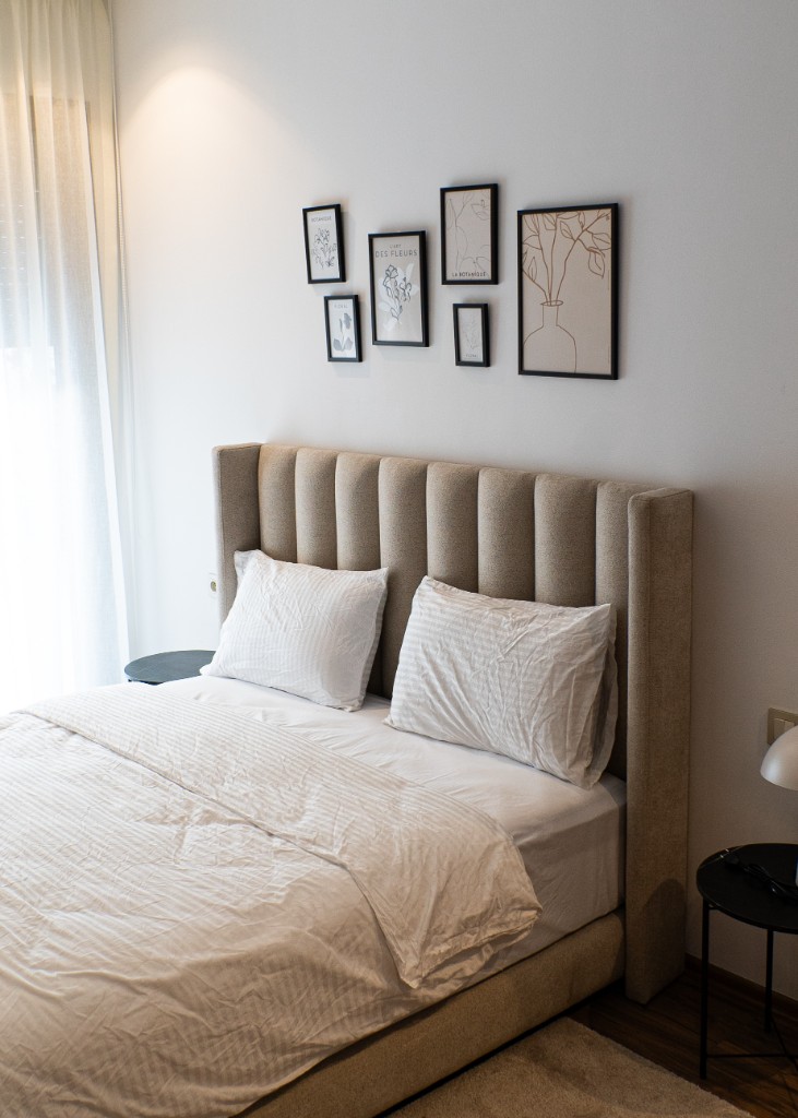 Chambre lumineuse avec tête de lit beige, voilages et tables de chevet noires — Marrakech