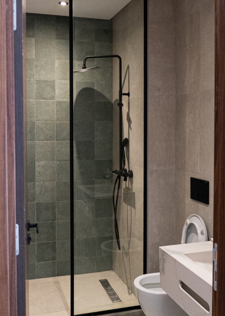 Salle de bain moderne avec douche à l’italienne, robinetterie noire et vasque suspendue — Marrakech