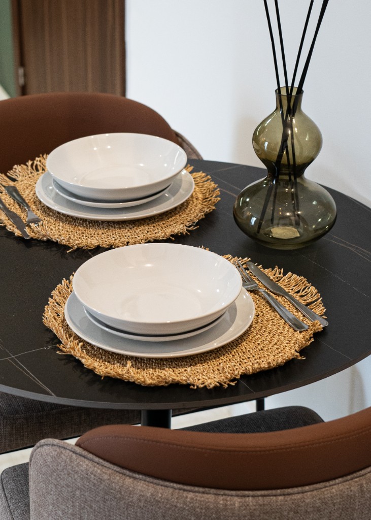 Détail d’une table à manger dressée avec sets en paille et vase en verre teinté — Marrakech