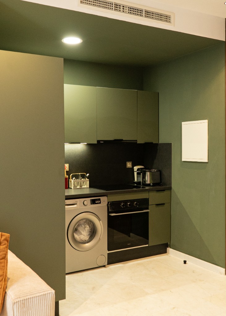 Cuisinette moderne aux placards vert sauge avec plan de travail noir et électroménager intégré — Marrakech