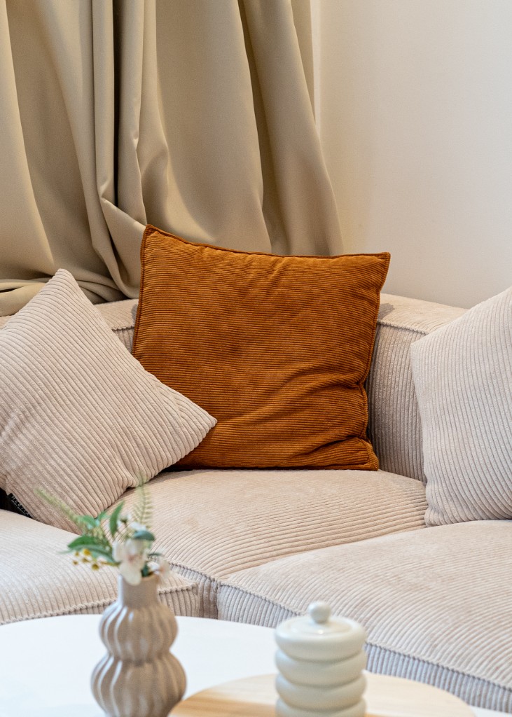 Détail d’un canapé beige avec coussin terracotta et vase décoratif — Marrakech