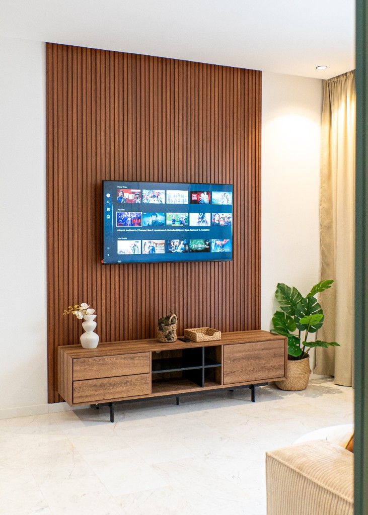 Mur TV en tasseaux de bois avec console basse et plante décorative — Marrakech