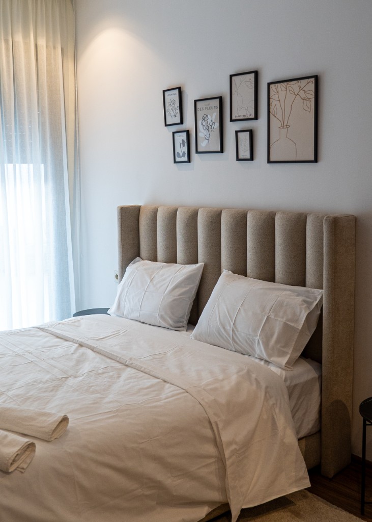 Chambre moderne lumineuse avec tête de lit capitonnée beige et décoration murale — Marrakech